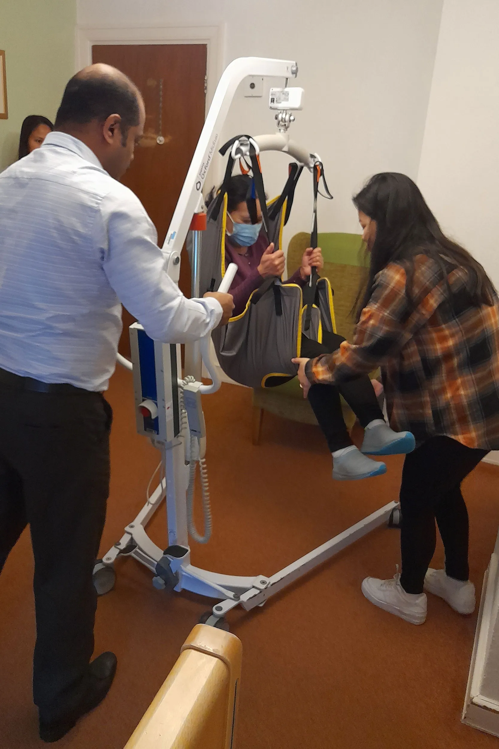 A man standing next to a woman in a chair.